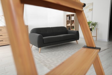 Photo of Comfortable sofa in living room, view through wooden ladder