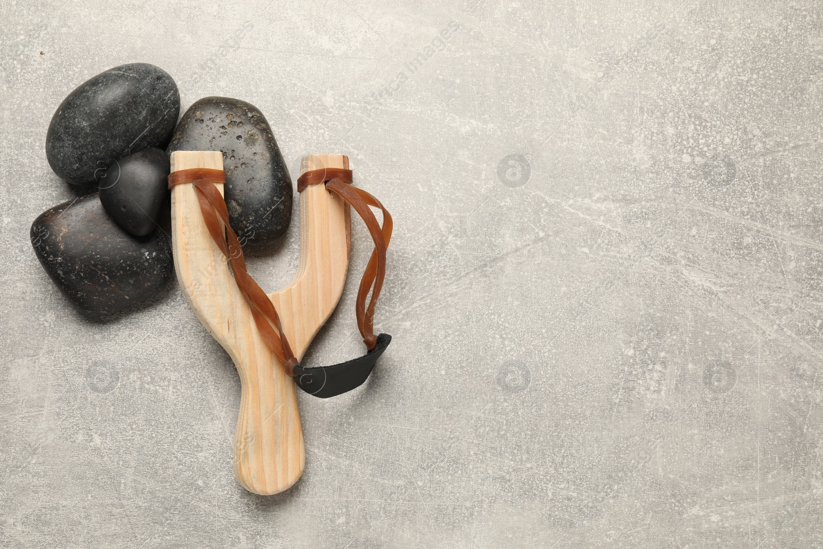 Photo of Slingshot with stones on light grey background, flat lay. Space for text