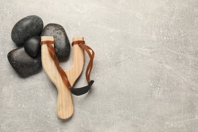 Slingshot with stones on light grey background, flat lay. Space for text