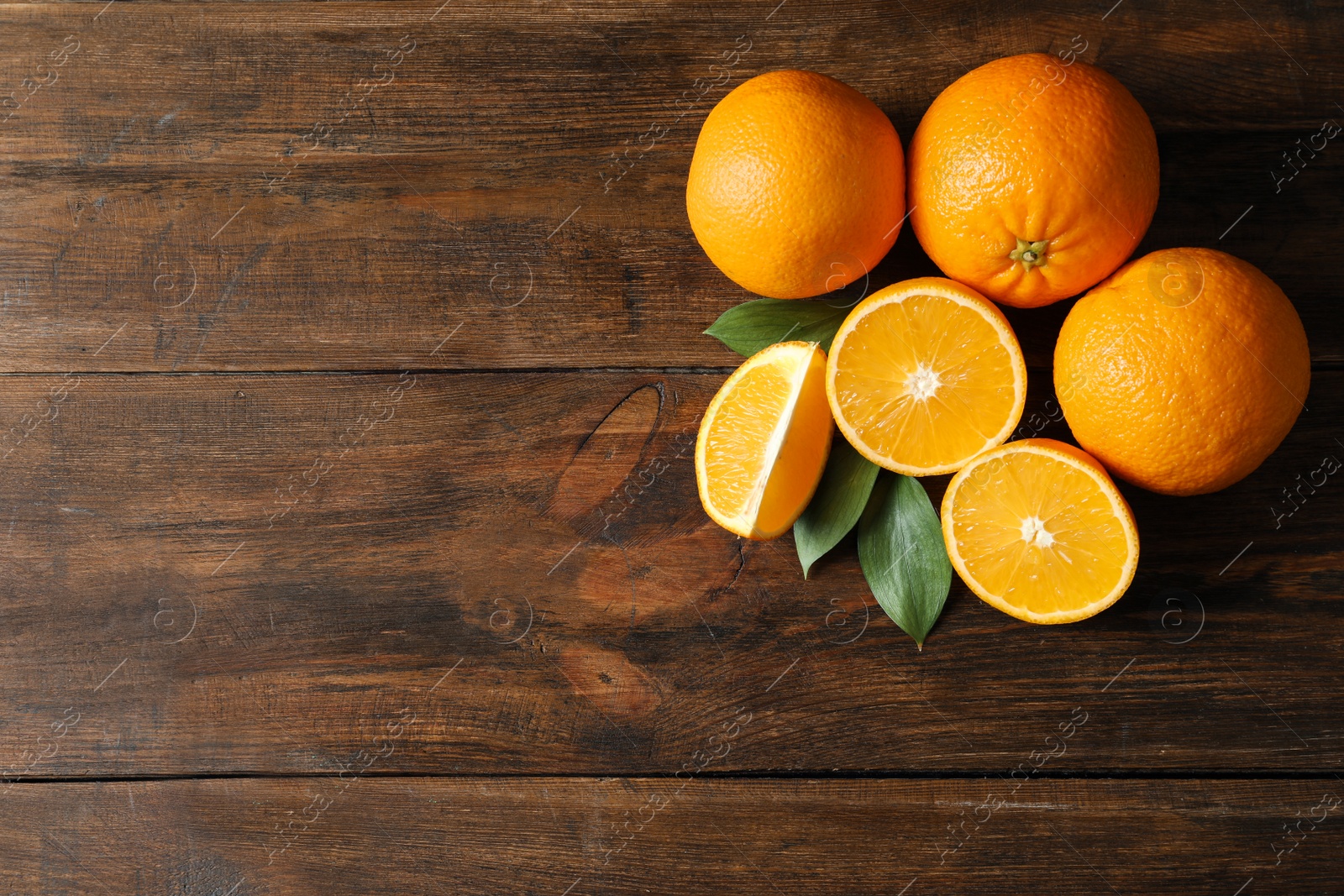 Photo of Fresh oranges with leaves on wooden background, top view. Space for text