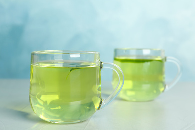 Photo of Cups of aromatic green tea on light table