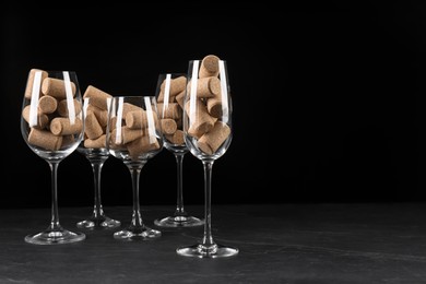 Glasses full of wine corks on black table. Space for text