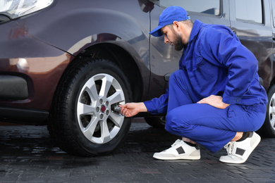 Mechanic checking tire air pressure at car service