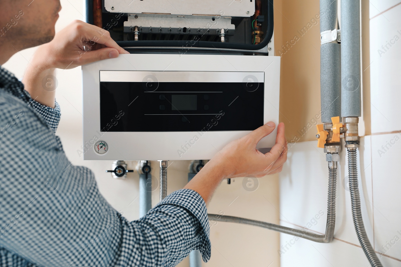 Photo of Man opening top of gas boiler indoors, closeup