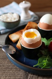 Photo of Delicious breakfast with soft boiled eggs served on wooden table, closeup