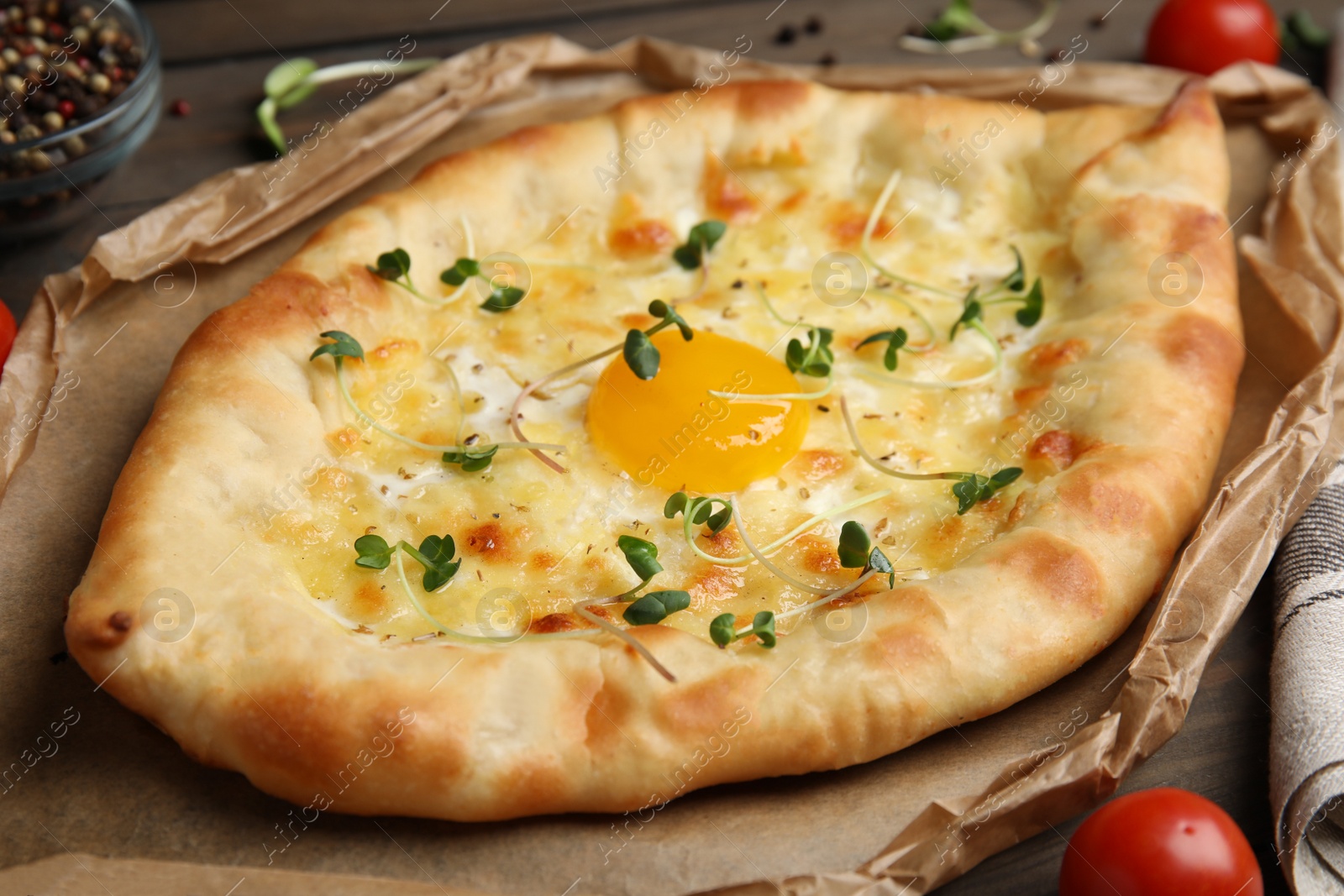 Photo of Fresh delicious Adjarian khachapuri served on wooden table, closeup