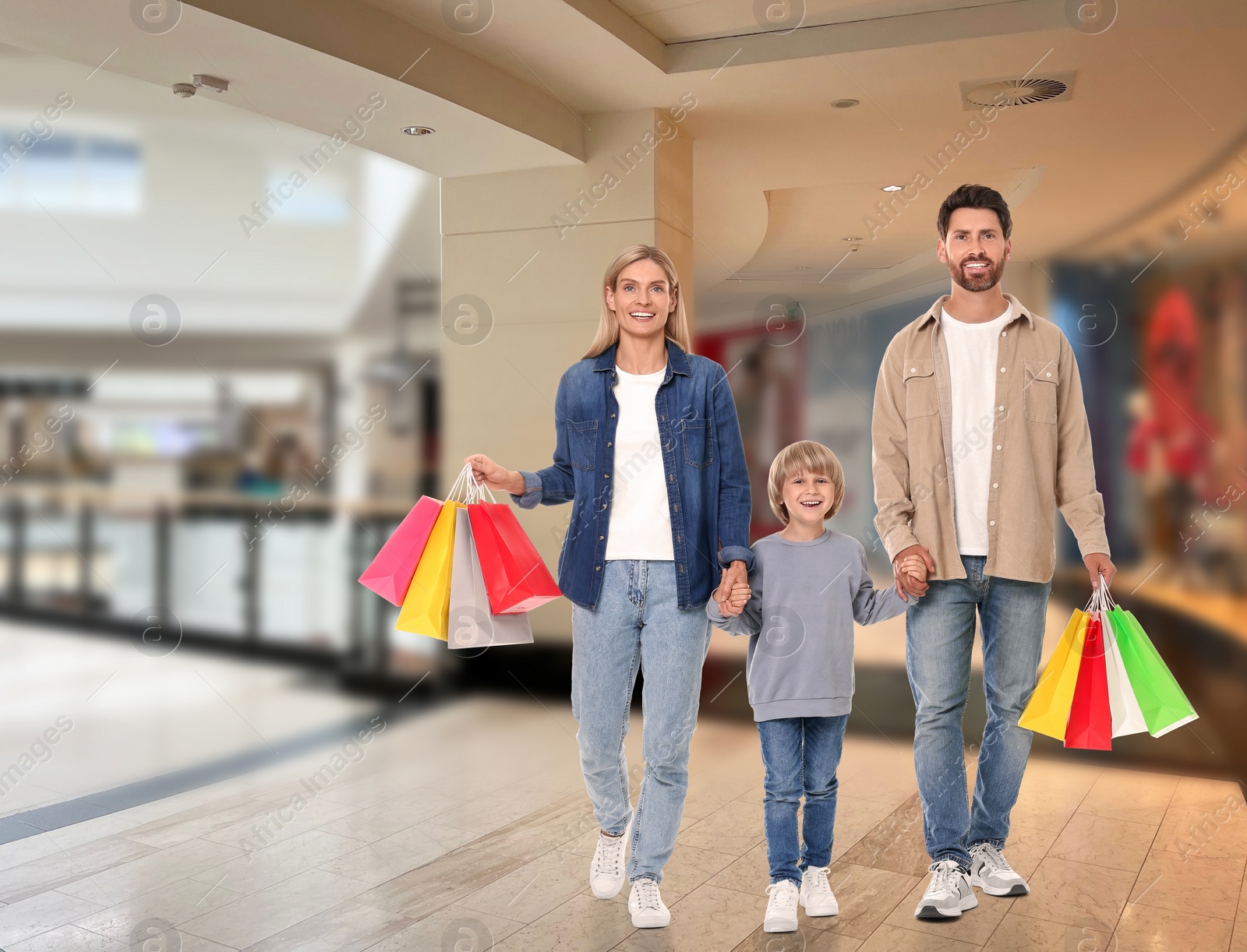 Image of Happy family with shopping bags walking in mall