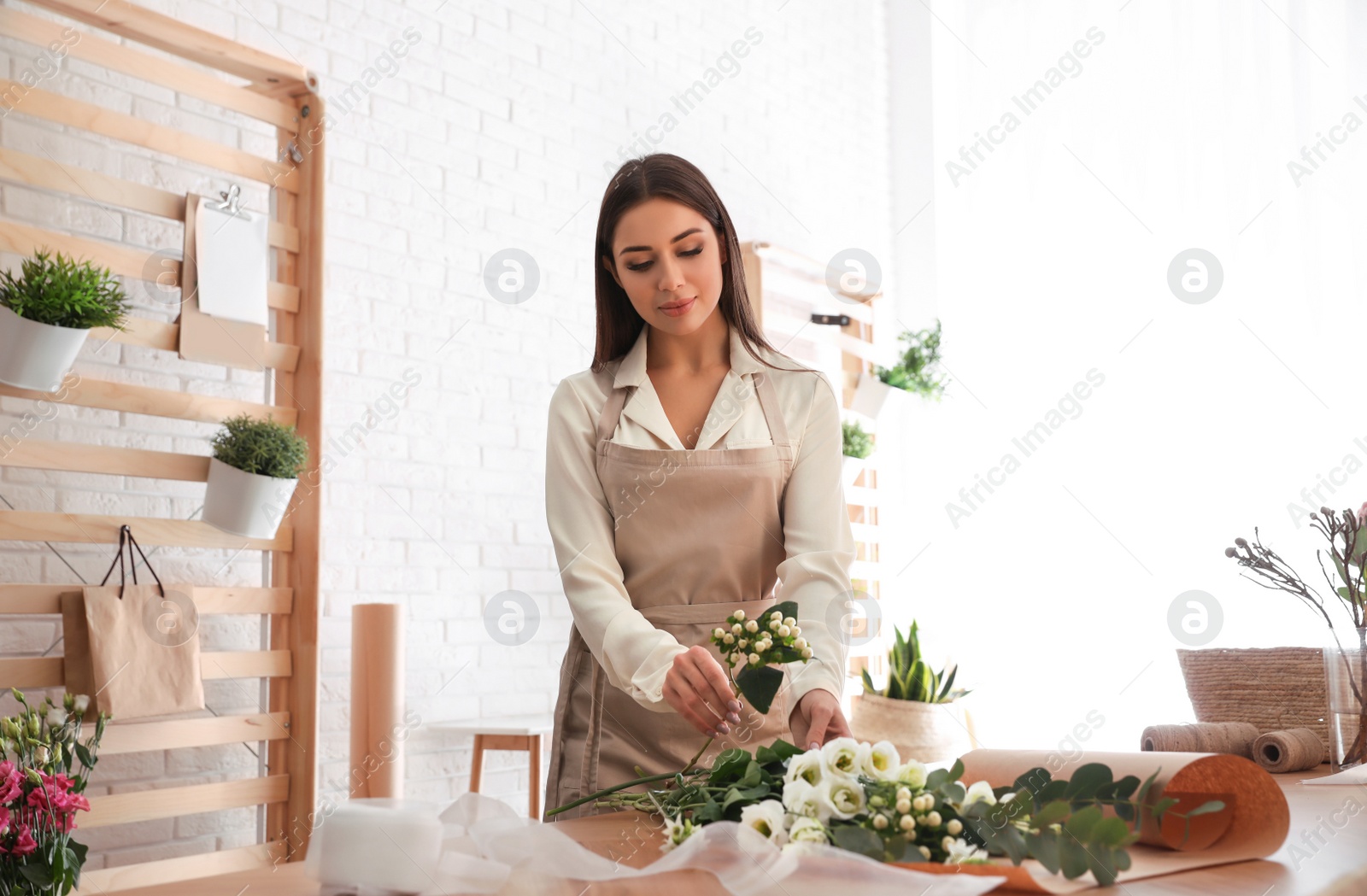 Photo of Florist making beautiful bouquet at table in workshop