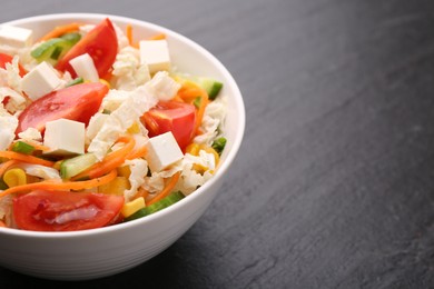 Photo of Tasty salad with Chinese cabbage, carrot, cheese, cucumber, corn and tomato on black table, closeup. Space for text