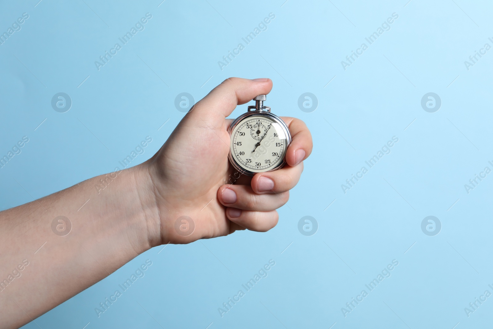 Photo of Man holding vintage timer on light blue background, closeup