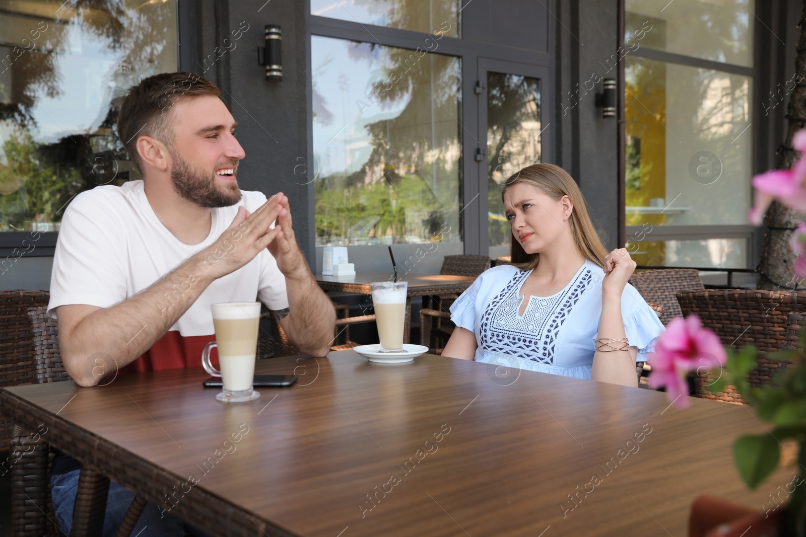 Photo of Young woman having boring date with guy in outdoor cafe