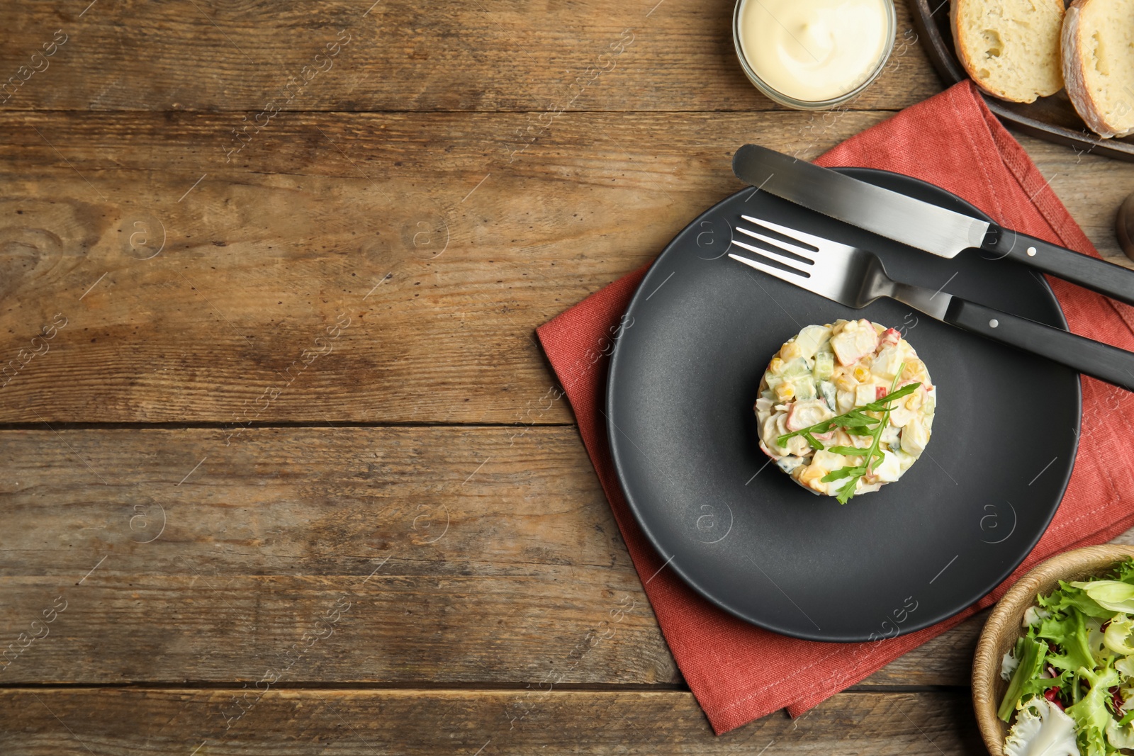 Photo of Delicious salad with crab sticks served on wooden table, flat lay. Space for text