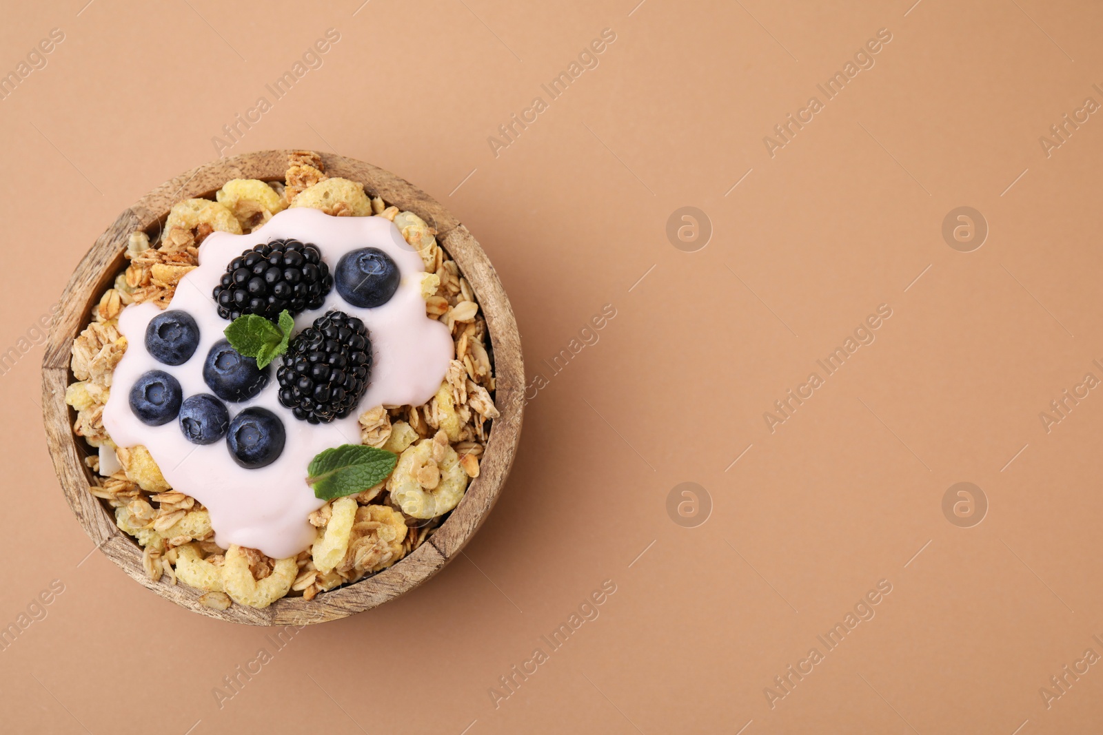 Photo of Tasty granola, yogurt and fresh berries in bowl on pale brown background, top view with space for text. Healthy breakfast