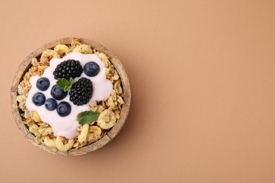 Tasty granola, yogurt and fresh berries in bowl on pale brown background, top view with space for text. Healthy breakfast