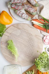 Rice paper and other ingredients for spring rolls on white wooden table, top view