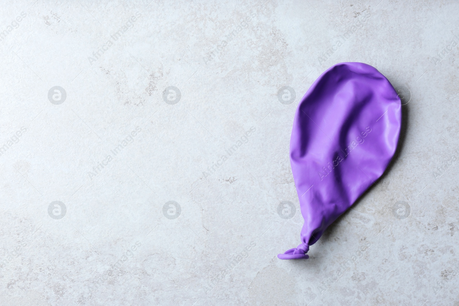 Photo of Purple deflated balloon on grey background, top view with space for text