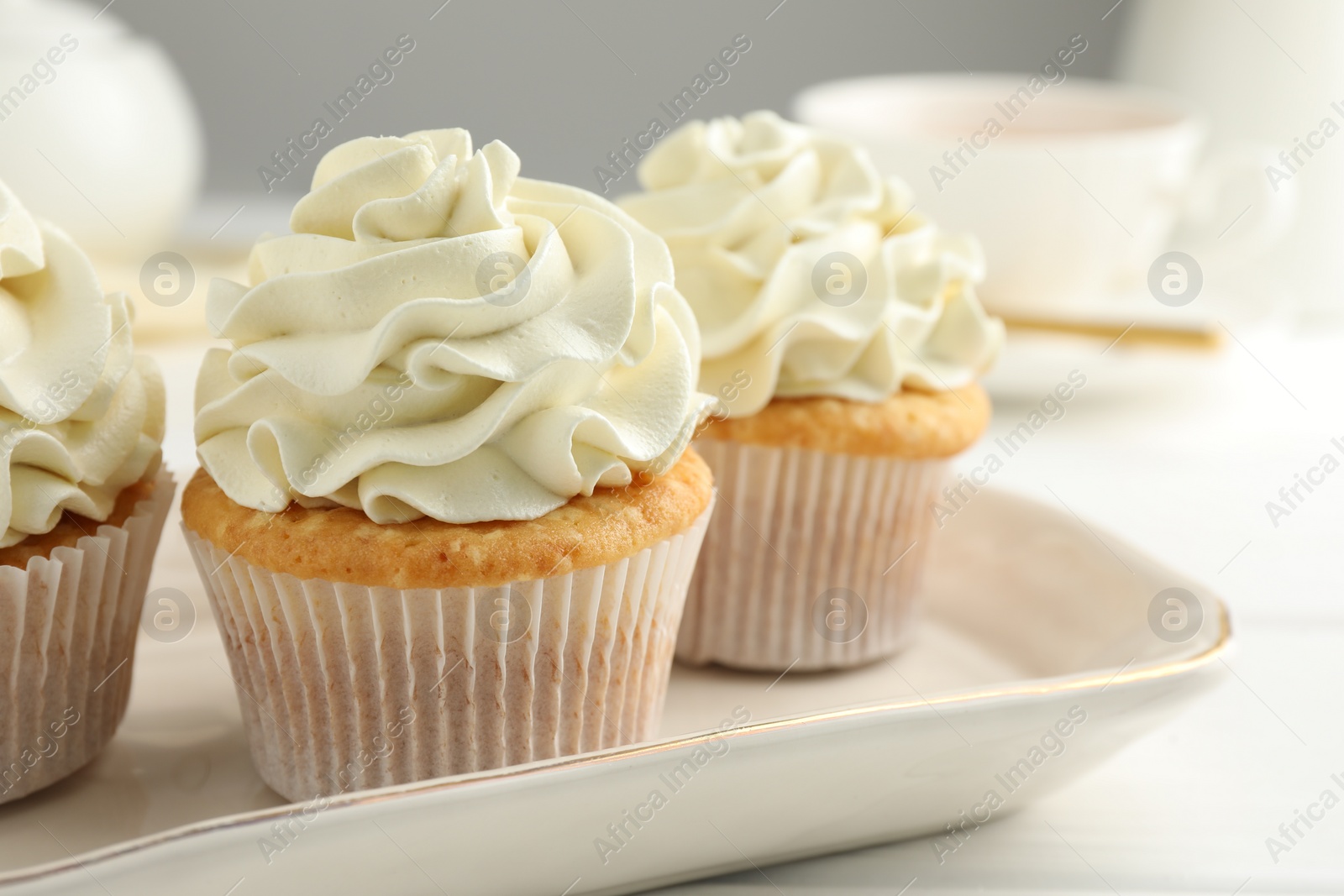 Photo of Tasty cupcakes with vanilla cream on white wooden table, closeup