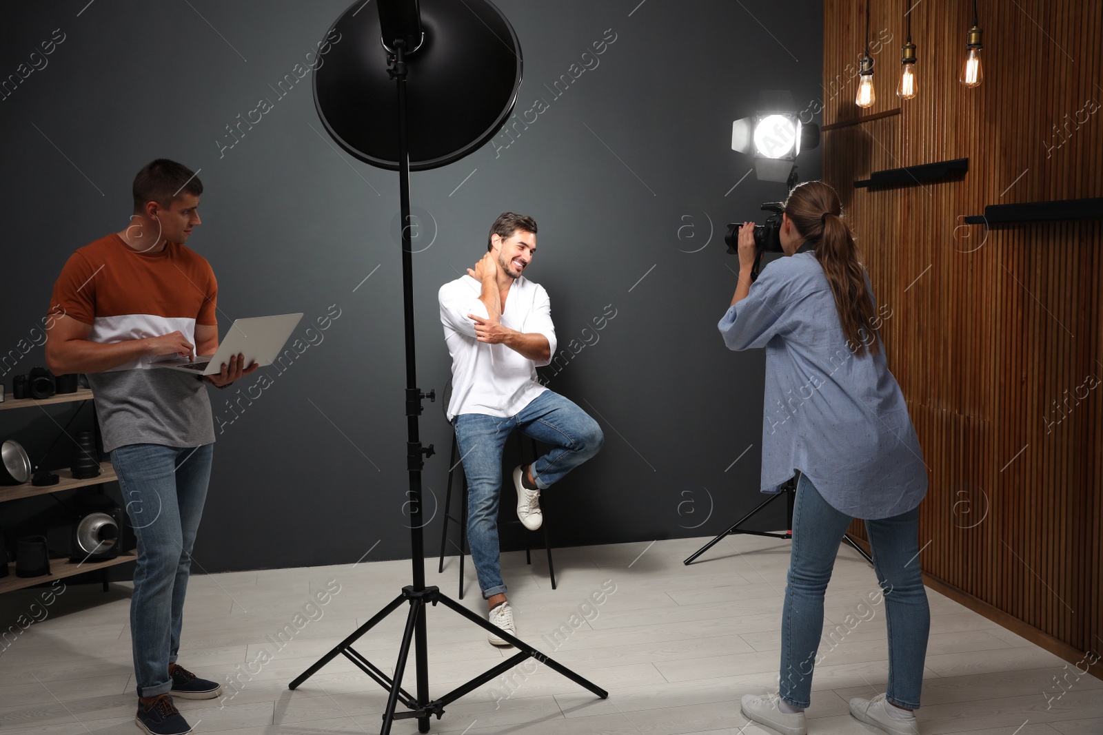 Photo of Professional photographer with assistant taking picture of young man in modern studio