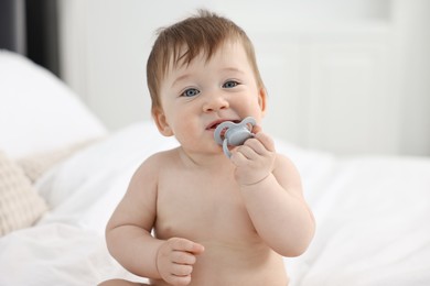 Photo of Cute baby boy with pacifier on bed at home