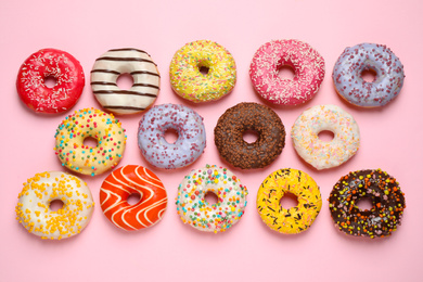 Delicious glazed donuts on pink background, flat lay