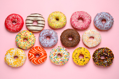 Photo of Delicious glazed donuts on pink background, flat lay