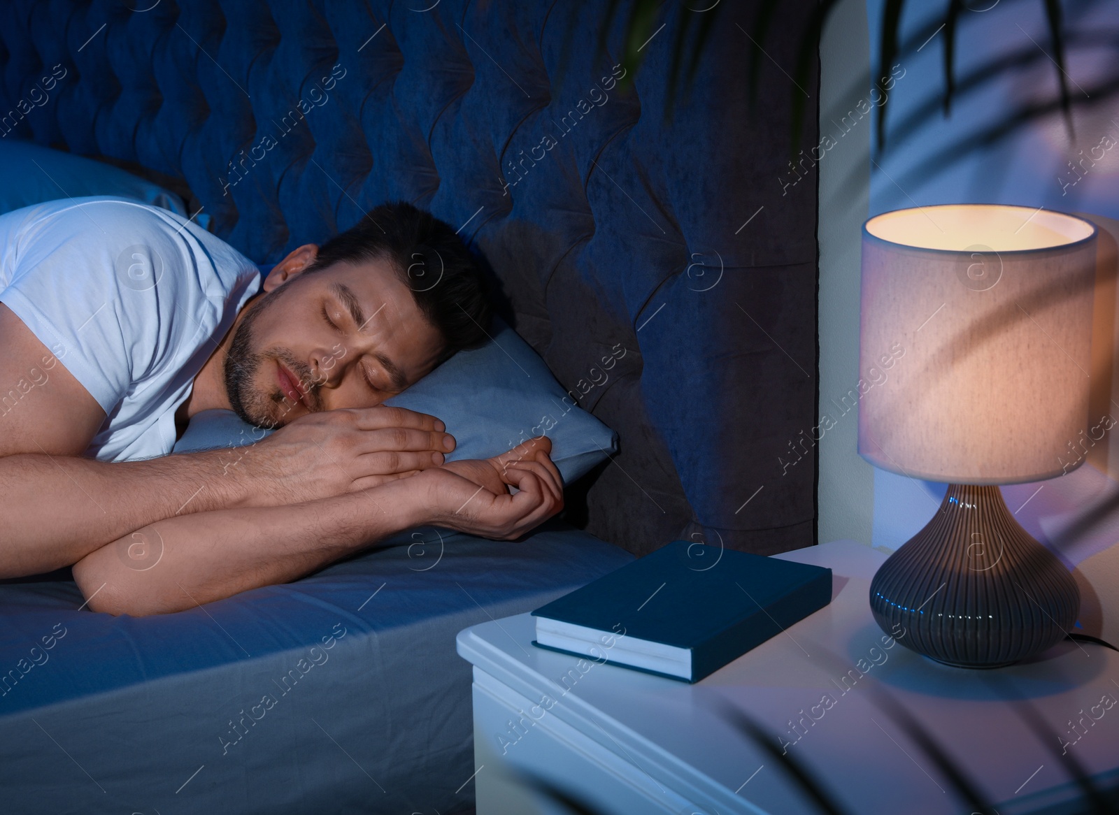 Photo of Handsome man sleeping on pillow in dark room at night. Bedtime