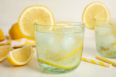 Soda water with lemon slices and ice cubes on white table