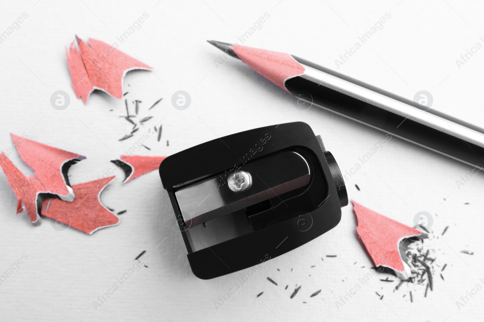 Photo of Pencil, sharpener and shavings on white background, flat lay