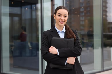 Photo of Female real estate agent with leather portfolio outdoors