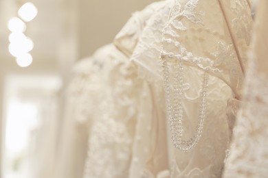 Beautiful wedding dresses with lace in salon, closeup