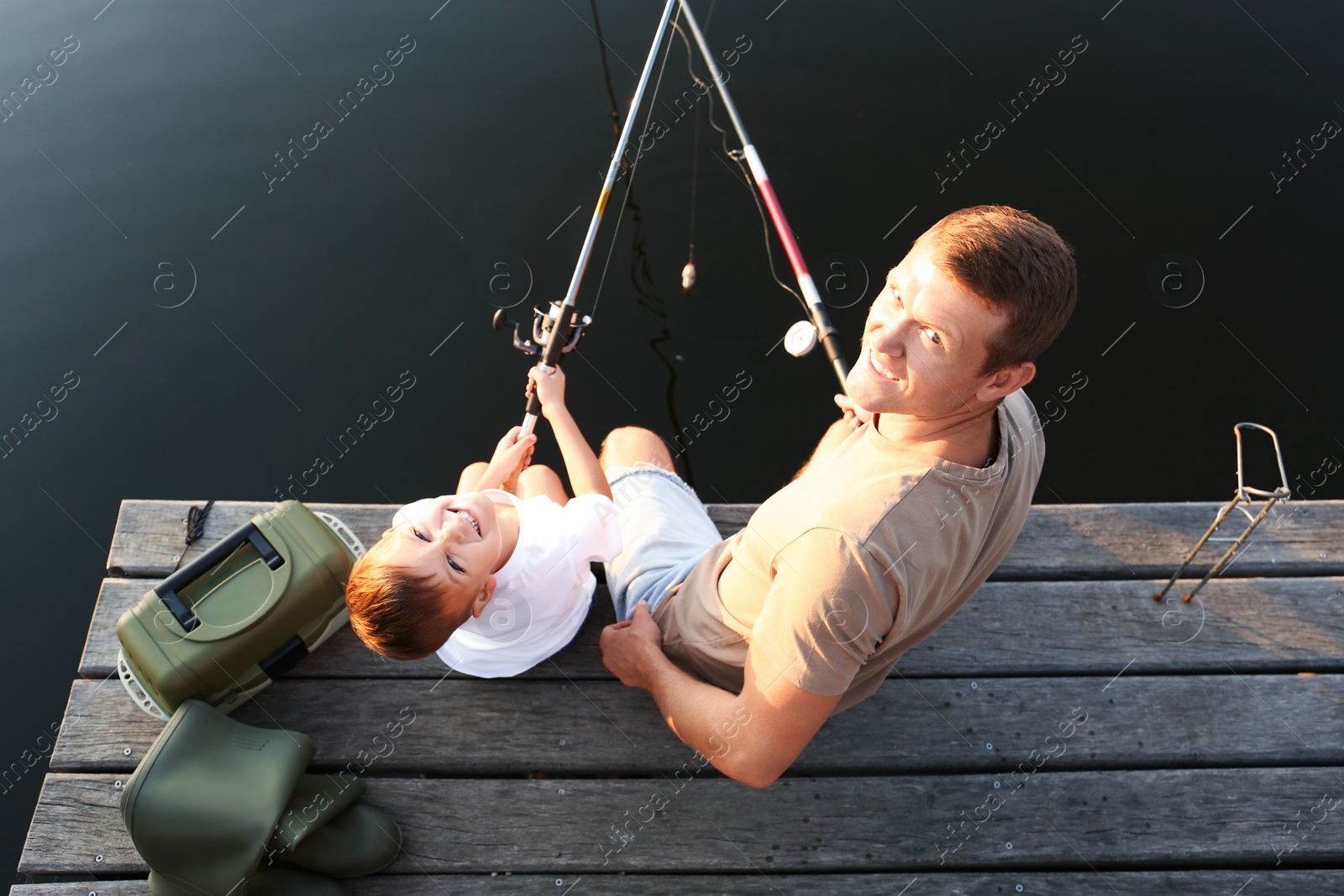 Photo of Dad and son fishing together at lake, above view
