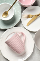 Photo of Beautiful ceramic dishware, cup and cutlery on light grey table, flat lay