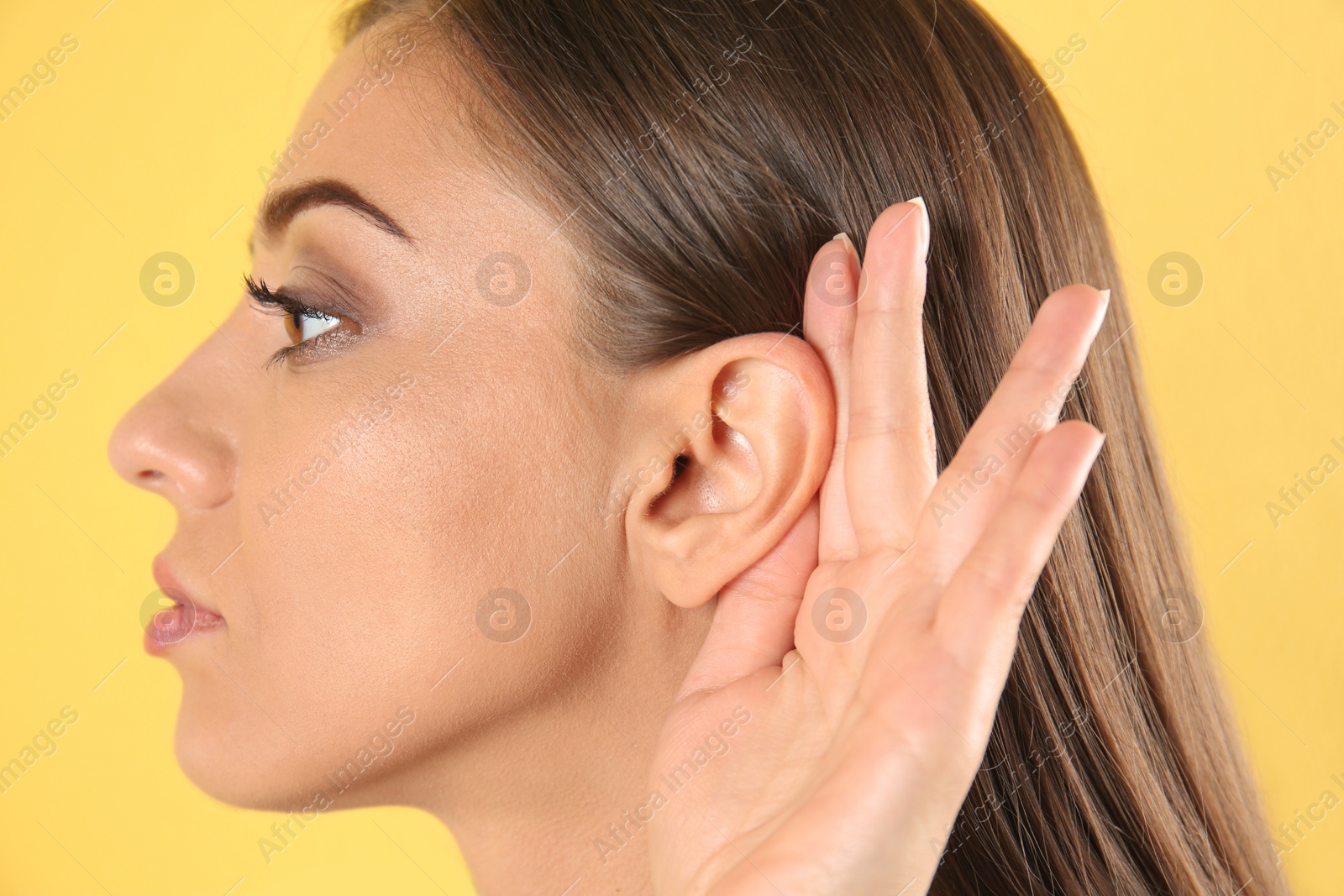 Photo of Young woman with hearing problem on color background, closeup