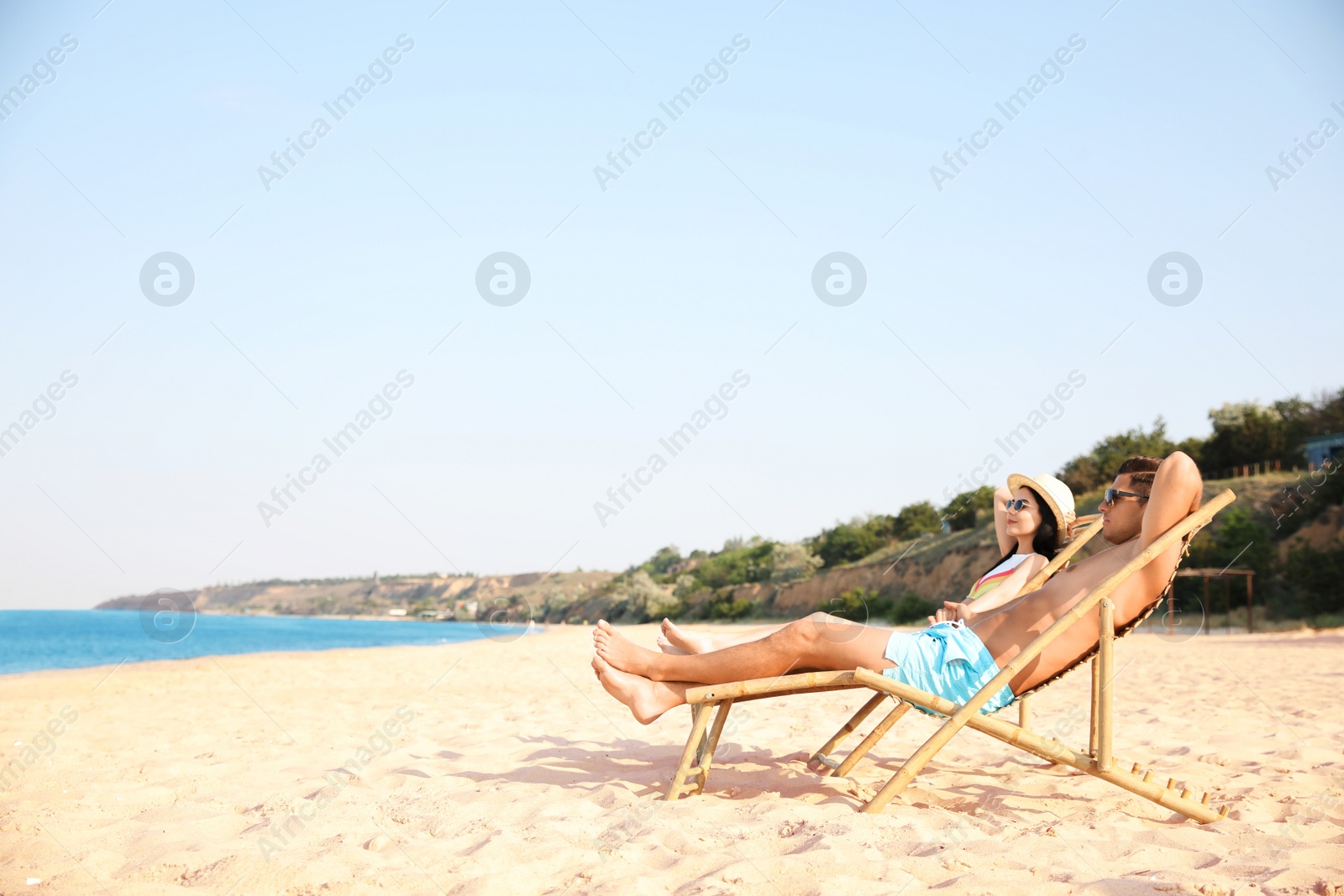 Photo of Couple resting on sunny beach at resort. Space for text