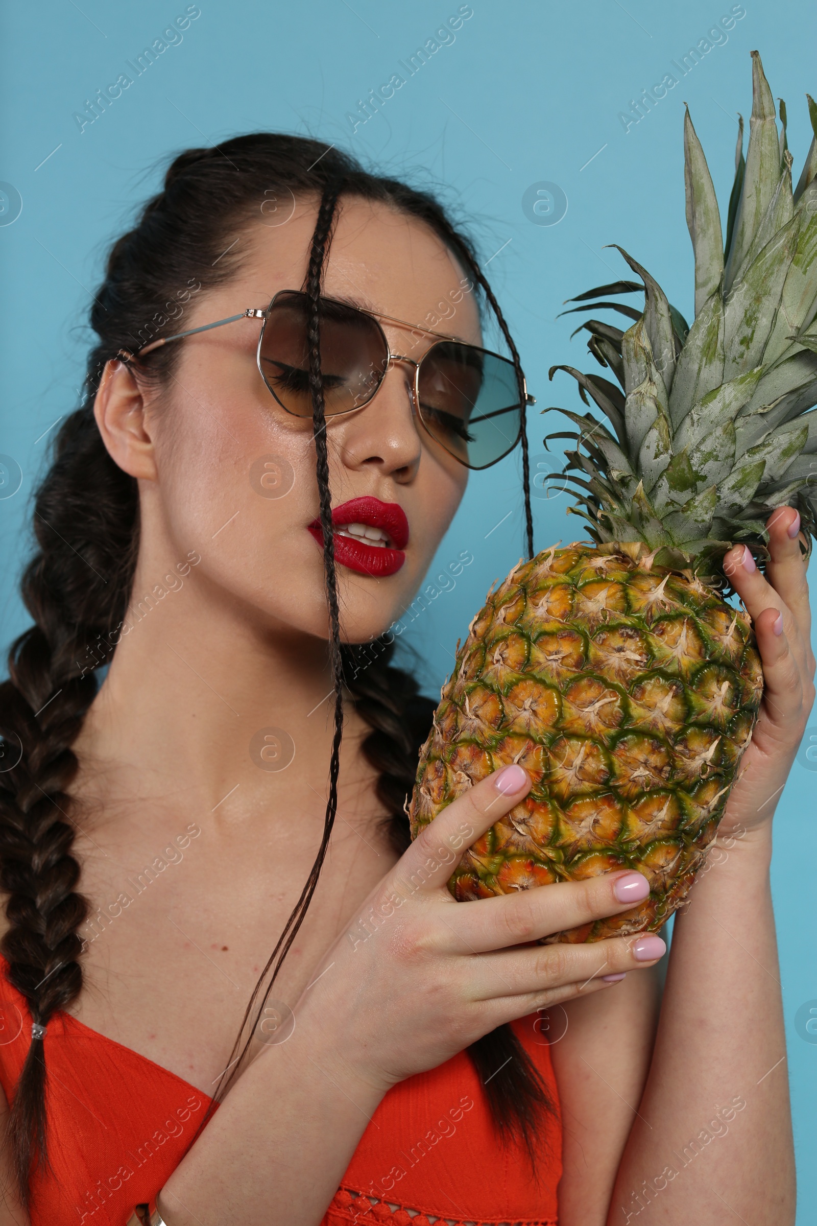 Photo of Young woman with fresh pineapple on light blue background. Exotic fruit