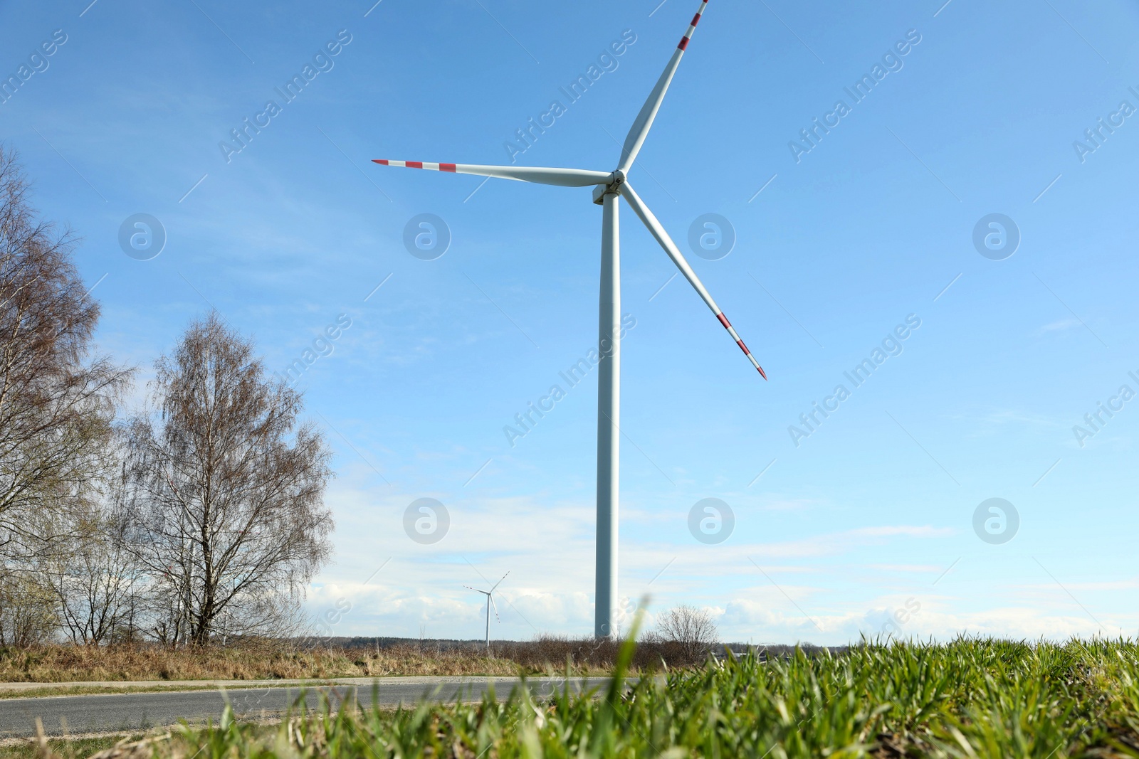 Photo of Modern wind turbines in field on sunny day. Alternative energy source