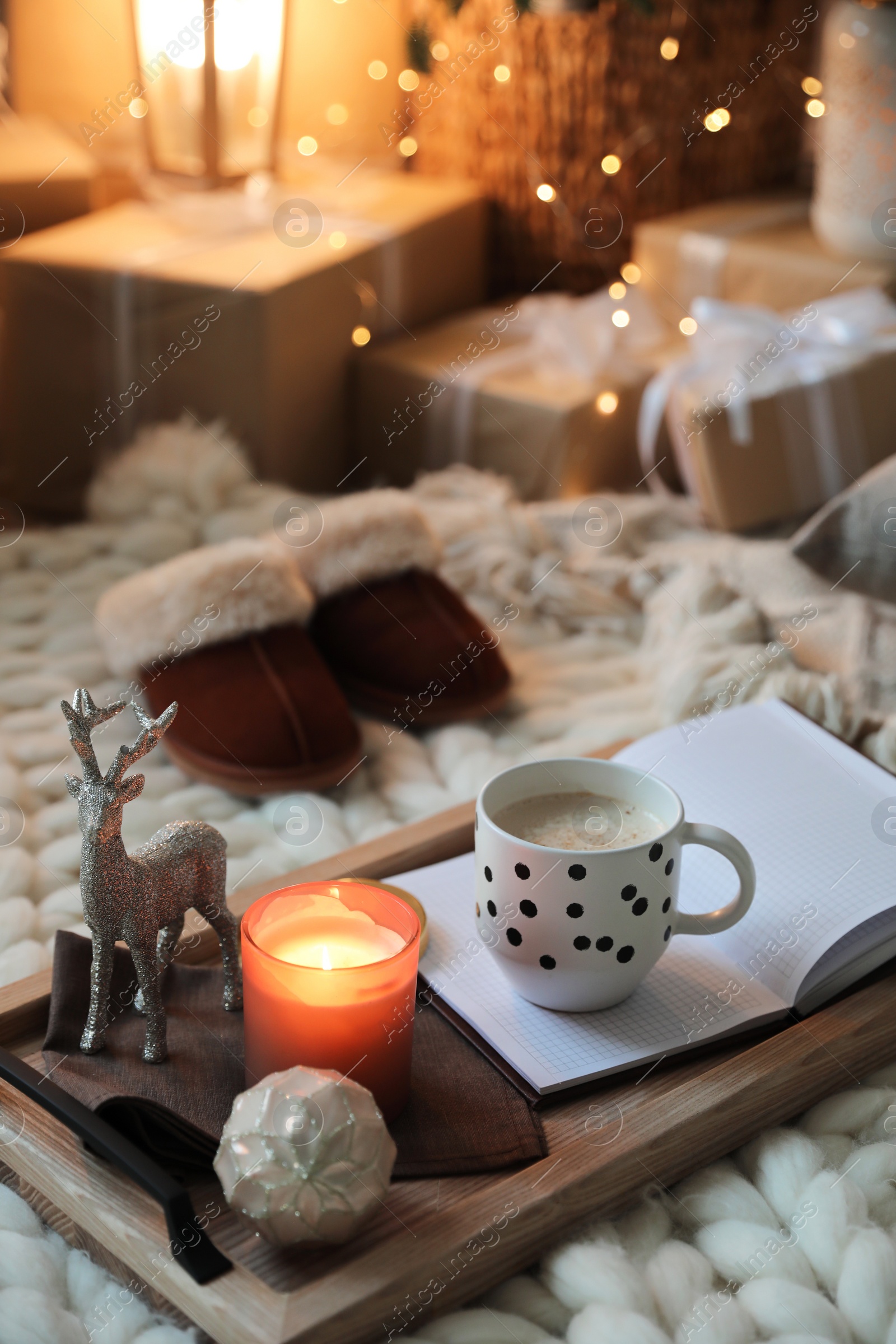 Photo of Wooden tray with cocoa, candle and notebook in room decorated for Christmas