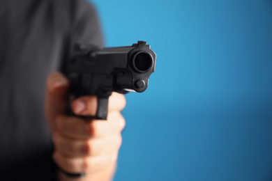 Man holding gun on blue background, closeup