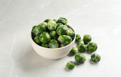 Photo of Frozen Brussels sprouts on light grey marble table. Vegetable preservation