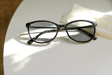 Stylish black eye glasses and cloth on white table. Space for text