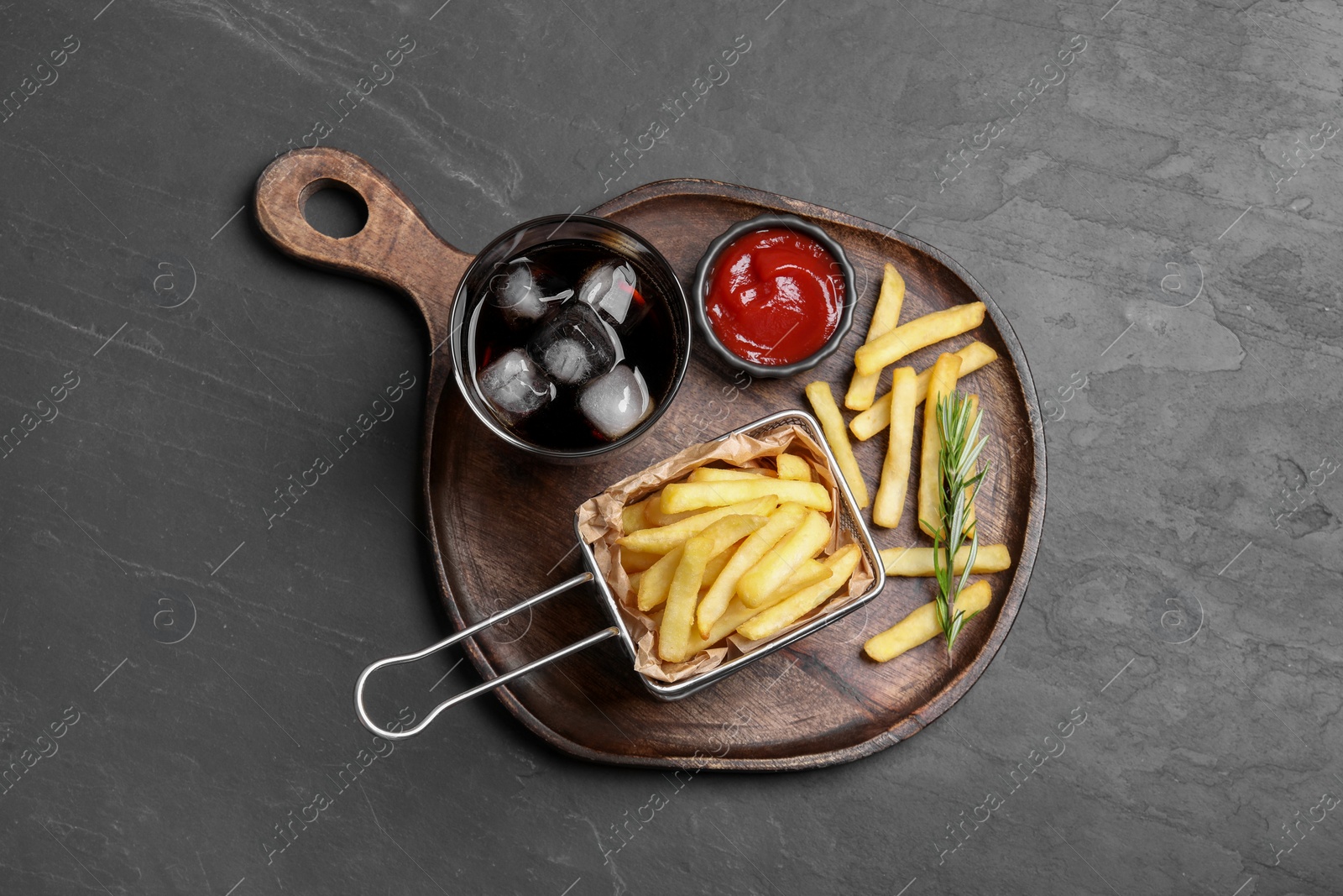 Photo of Tasty french fries, ketchup and soda drink on black table, top view