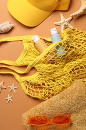 Photo of String bag and different beach accessories on pale orange background, flat lay