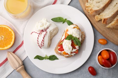 Photo of Delicious sandwich with burrata cheese and tomatoes served on grey table, flat lay