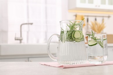 Photo of Refreshing cucumber water with rosemary on table in kitchen. Space for text