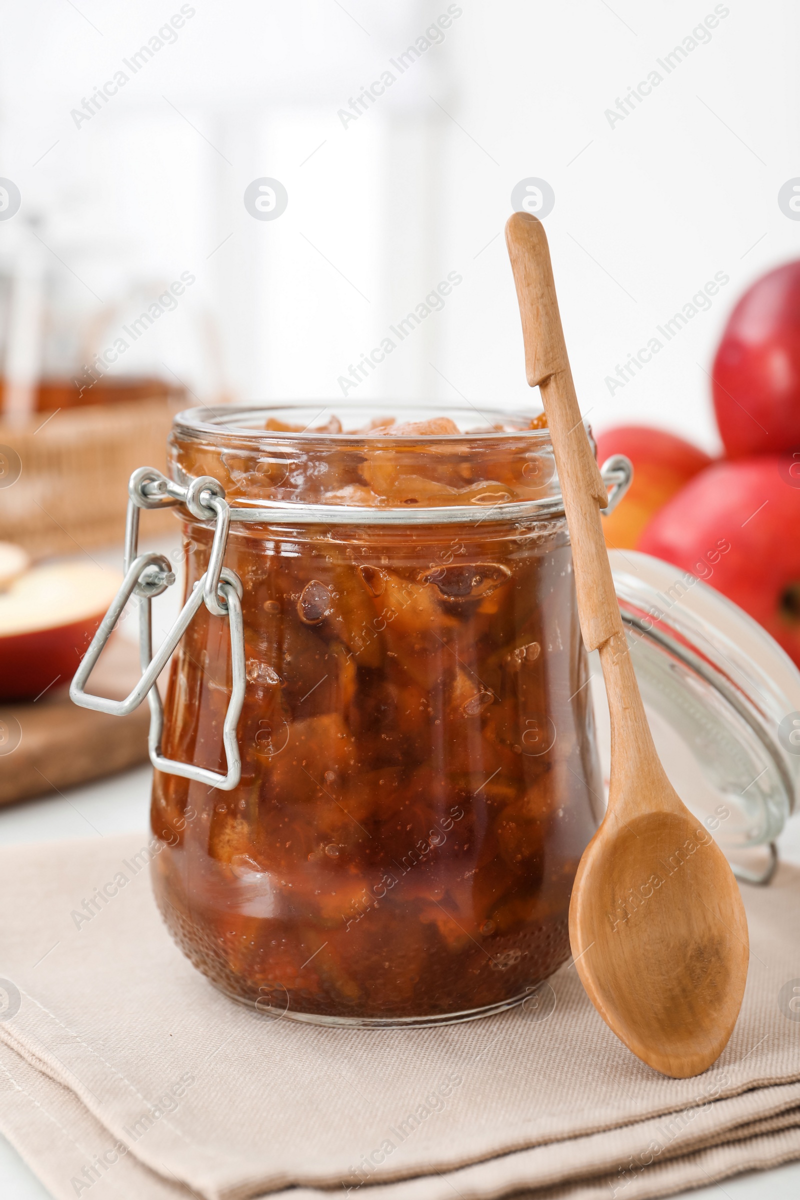 Photo of Delicious apple jam in jar and wooden spoon on table