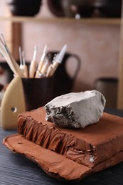 Clay on dark gray wooden table in workshop