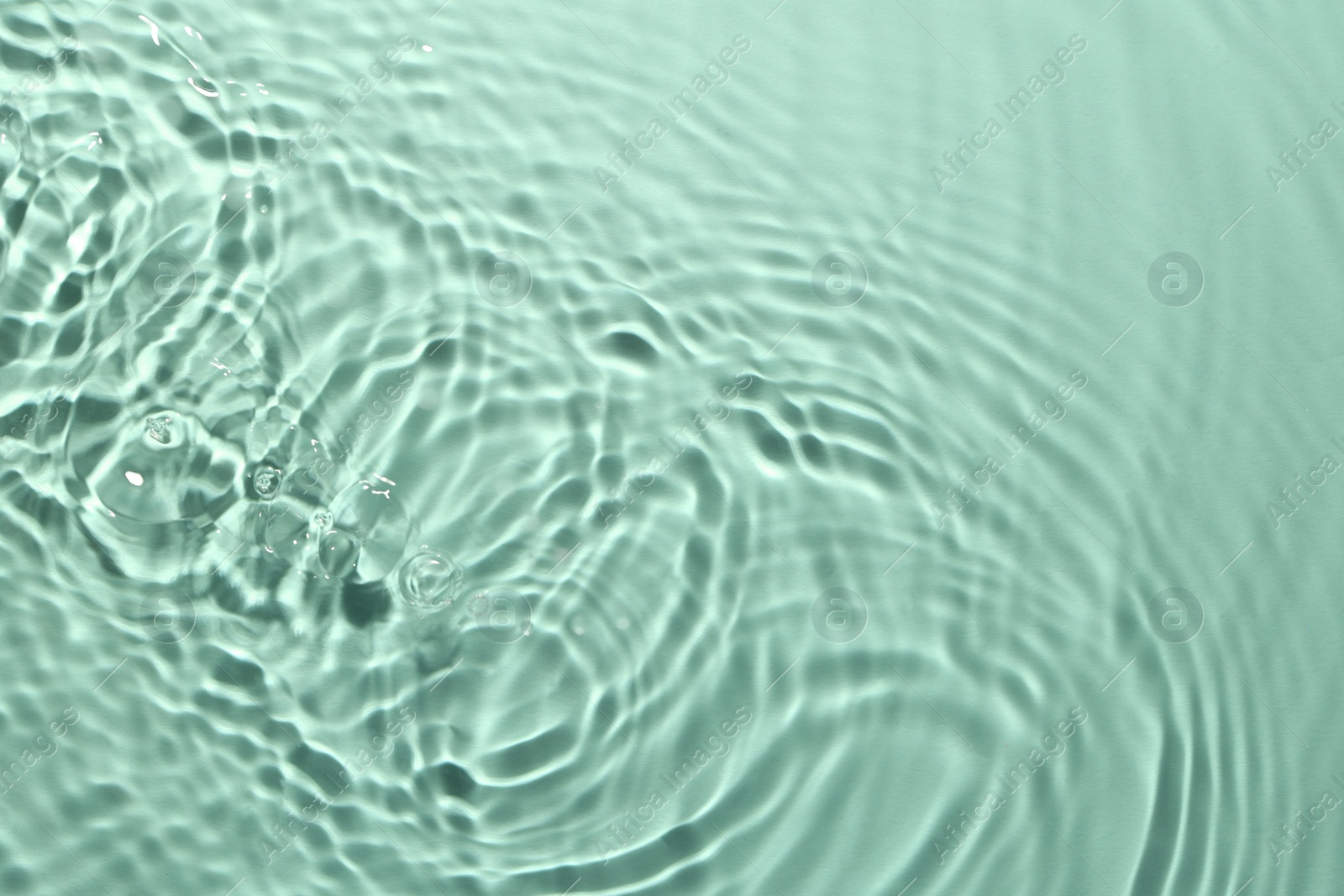 Image of Rippled surface of clear water on aquamarine background, top view