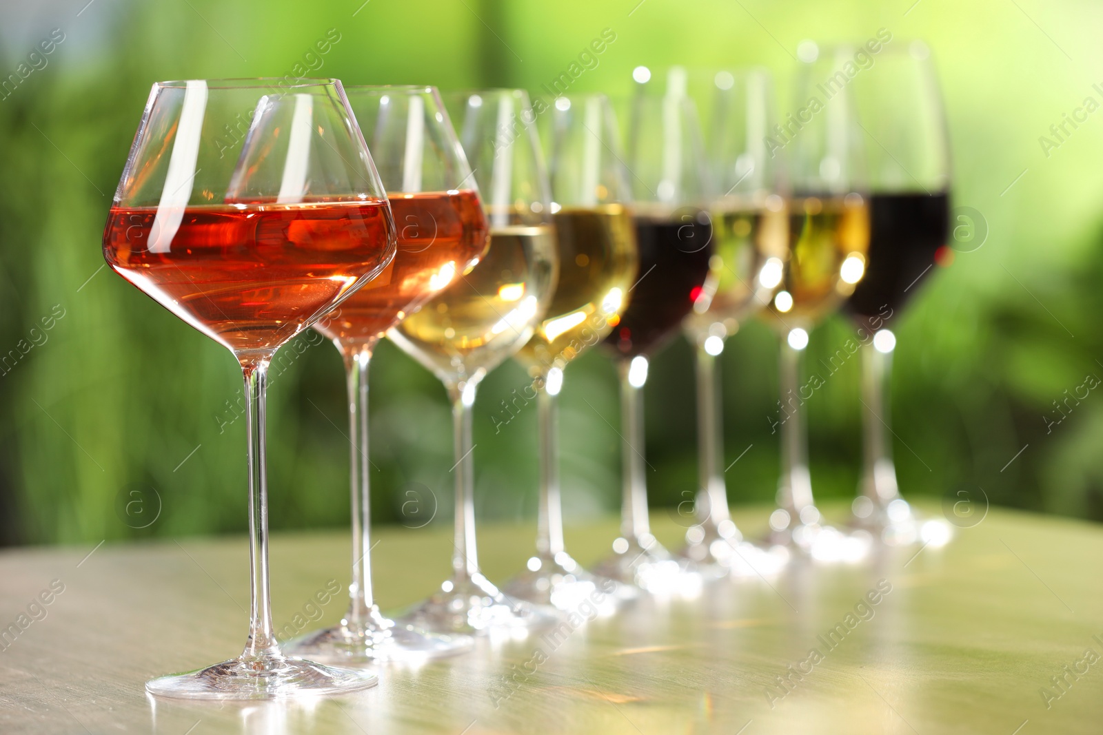 Photo of Different tasty wines in glasses on wooden table, space for text