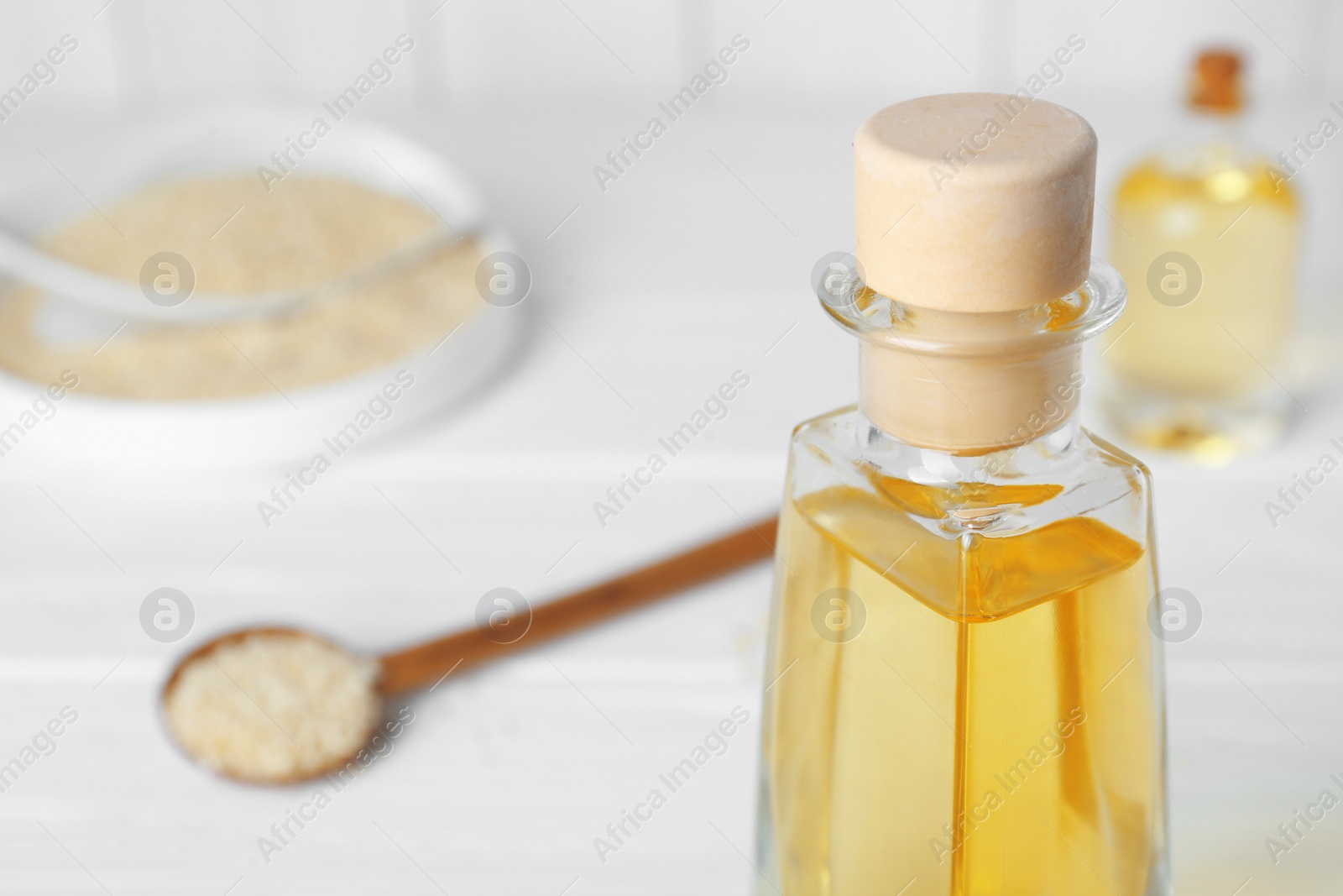 Photo of Glass bottle of sesame oil on white table, closeup. Space for text