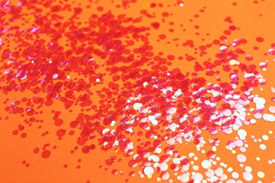 Photo of Shiny bright red glitter on orange background